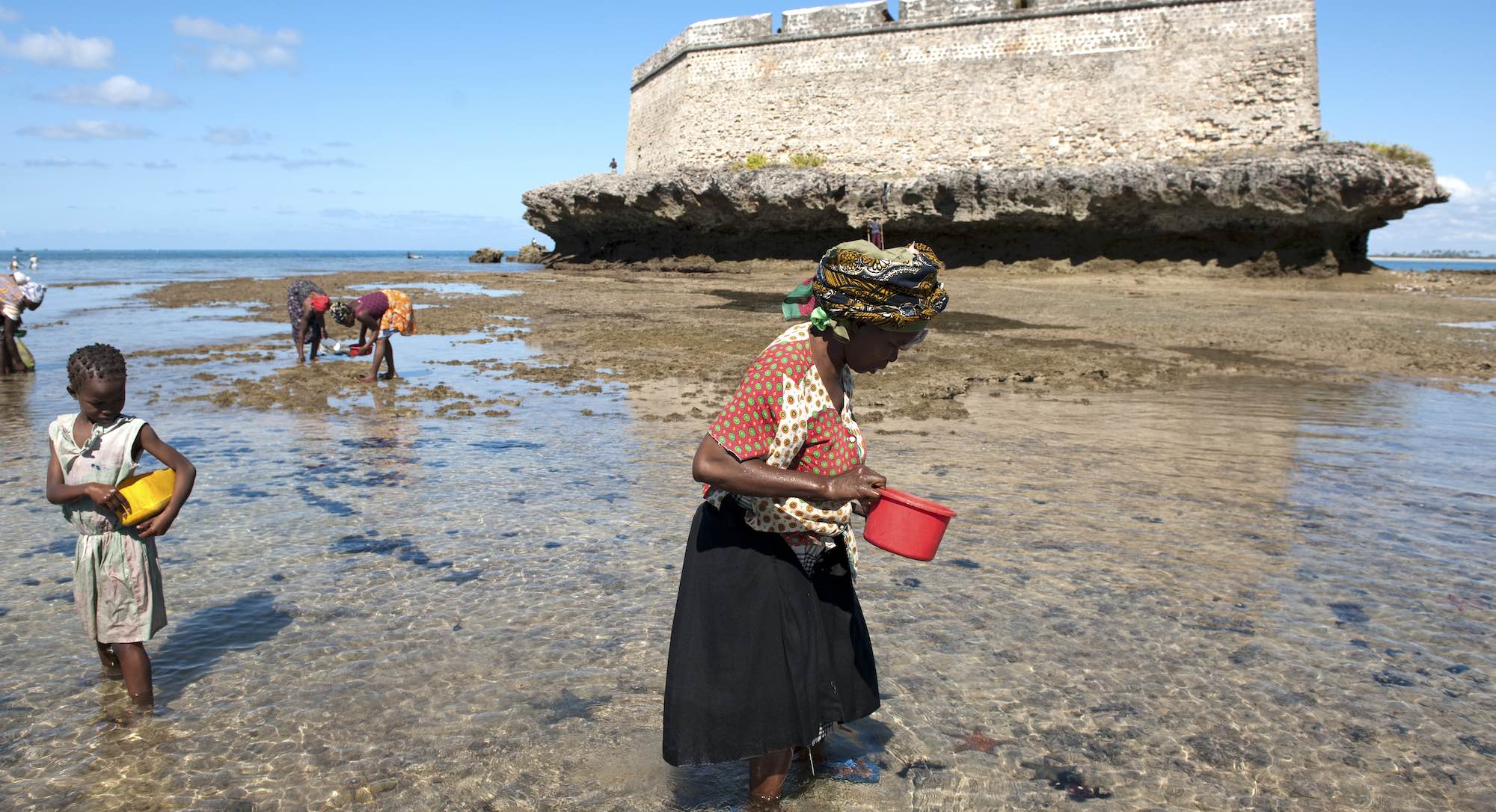Women and children looking for crustaceans in shallow water.