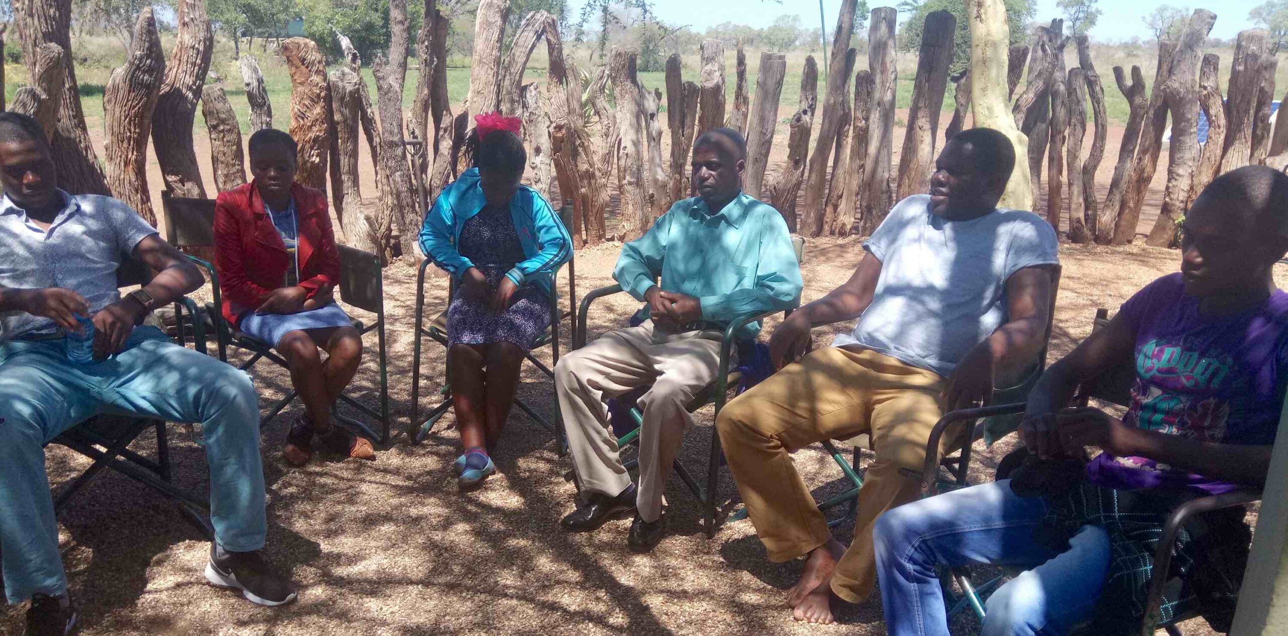 Six men and women sitting on chairs in a semi-circle.
