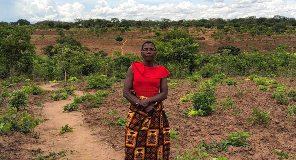 A woman in red, stands in front of a field of soya beans.
