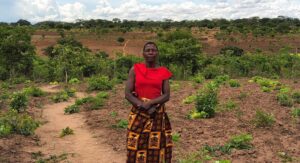 A woman in red, stands in front of a field of soya beans.